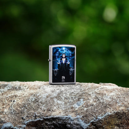 Lifestyle image of Zippo Anne Stokes Moon Witch Design Street Chrome Windproof Lighter standing on a rock showing the front of the lighter with an impressionistic green blur background. 

