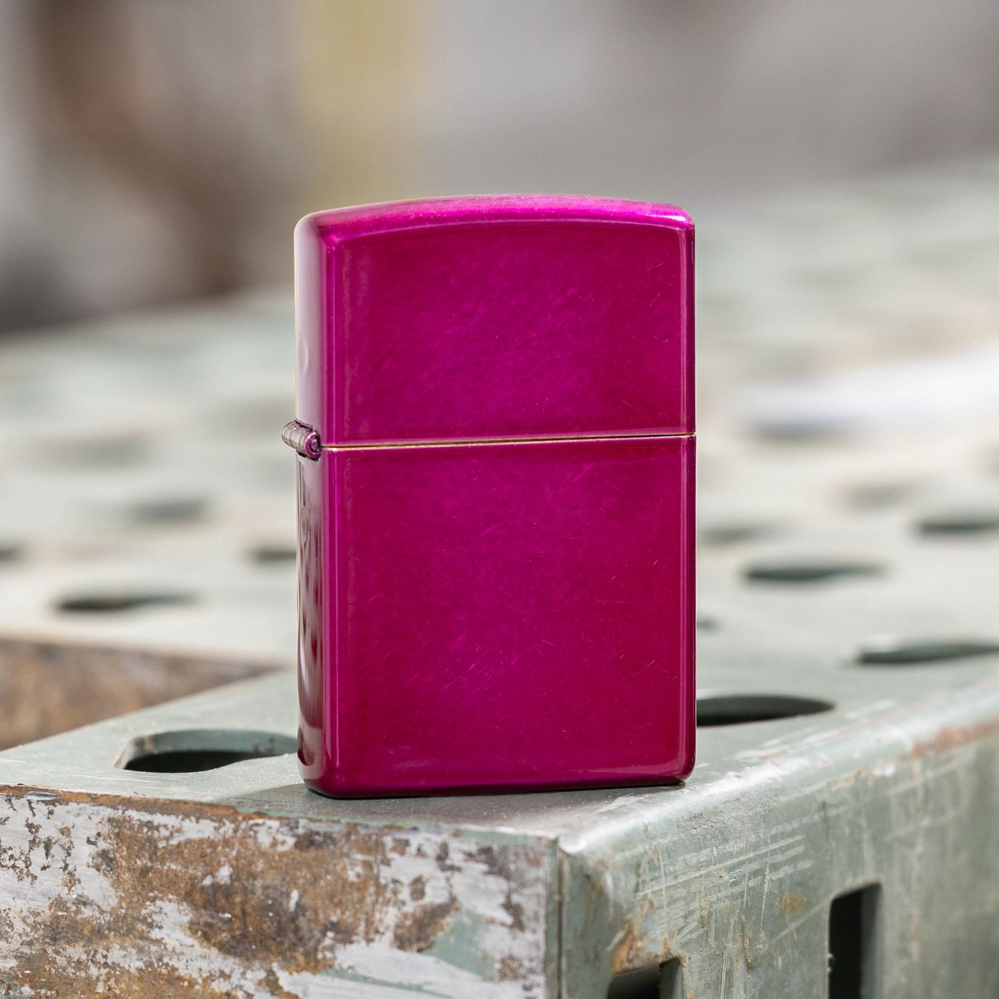 Lifestyle image of Zippo Classic Candy Raspberry Windproof Lighter standing on a welding table showing the front of the lighter. 

