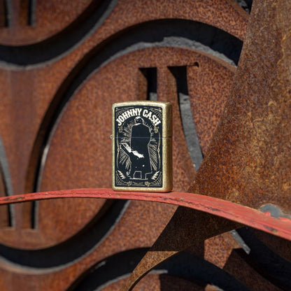 Lifestyle image of Zippo Johnny Cash Walk Design Street Brass Windproof Lighter standing in front of a rusty 3-D steel sculpture facade, showing the front of the lighter. 

