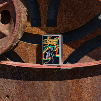 Lifestyle image of Zippo Bob Marley Waves Design Street Chrome Windproof Lighter standing on rusty gears while showing the front of the lighter with the rusty gears as the background. 

