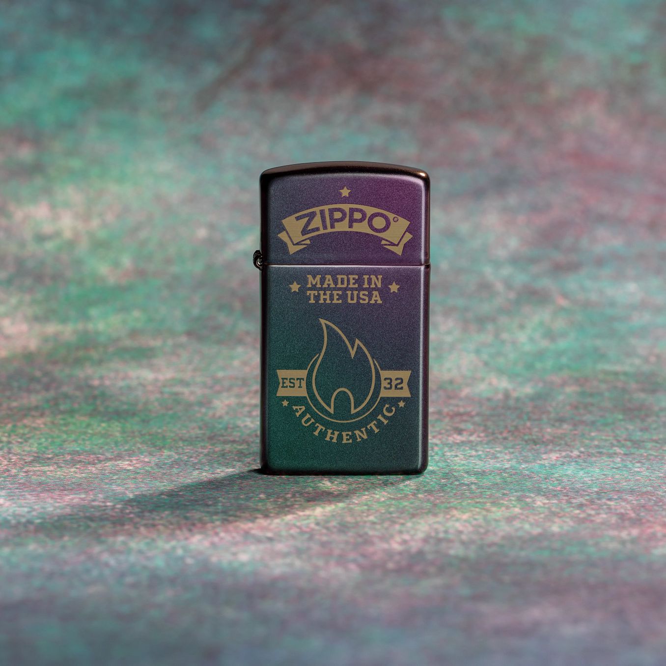 Lifestyle image of Zippo Authentic Zippo Design Slim Iridescent Windproof Lighter standing with a purple, teal, and grey background. 

