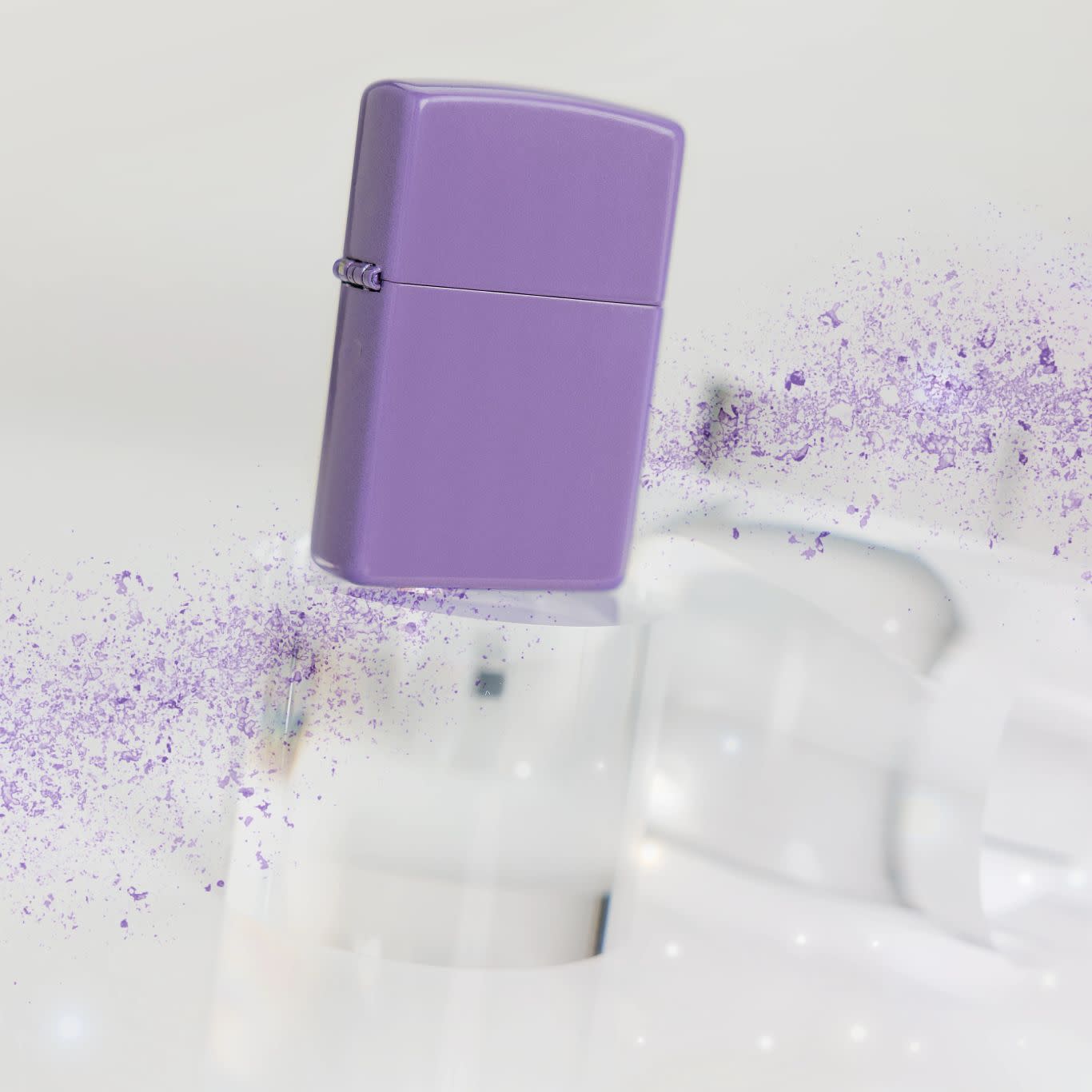 Lifestyle image of Zippo Classic Smoky Lavender Windproof Lighter standing on a clear cylinder with a spray of purple on either end.