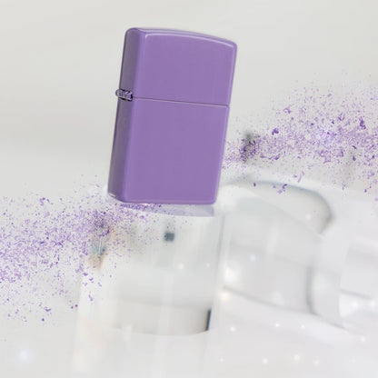 Lifestyle image of Zippo Classic Smoky Lavender Windproof Lighter standing on a clear cylinder with a spray of purple on either end.