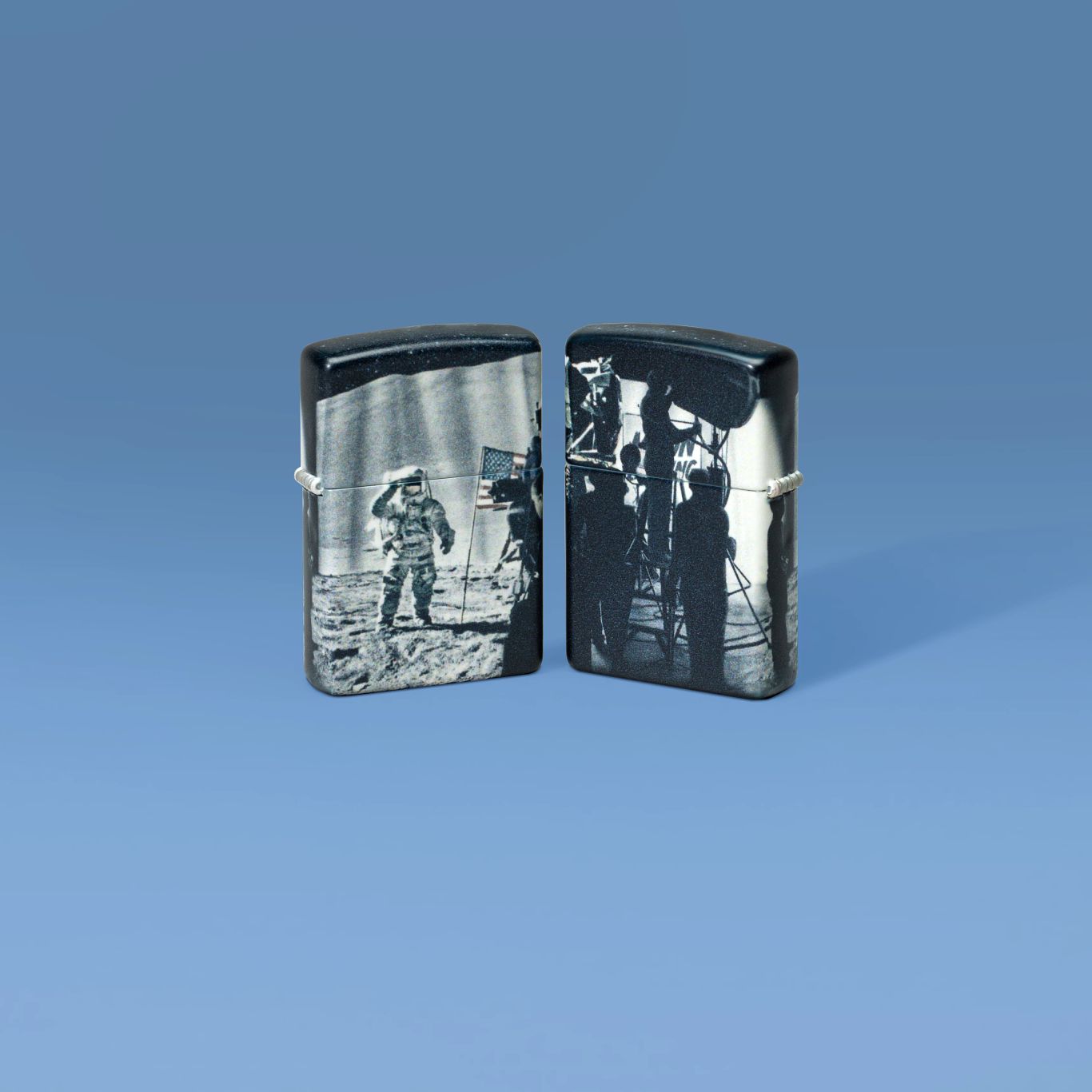 Lifestyle image of two Zippo Astro-not Design 540 Matte Windproof Lighters, one showing the front of the lighter and the other showing the back, standing against a denim blue background.