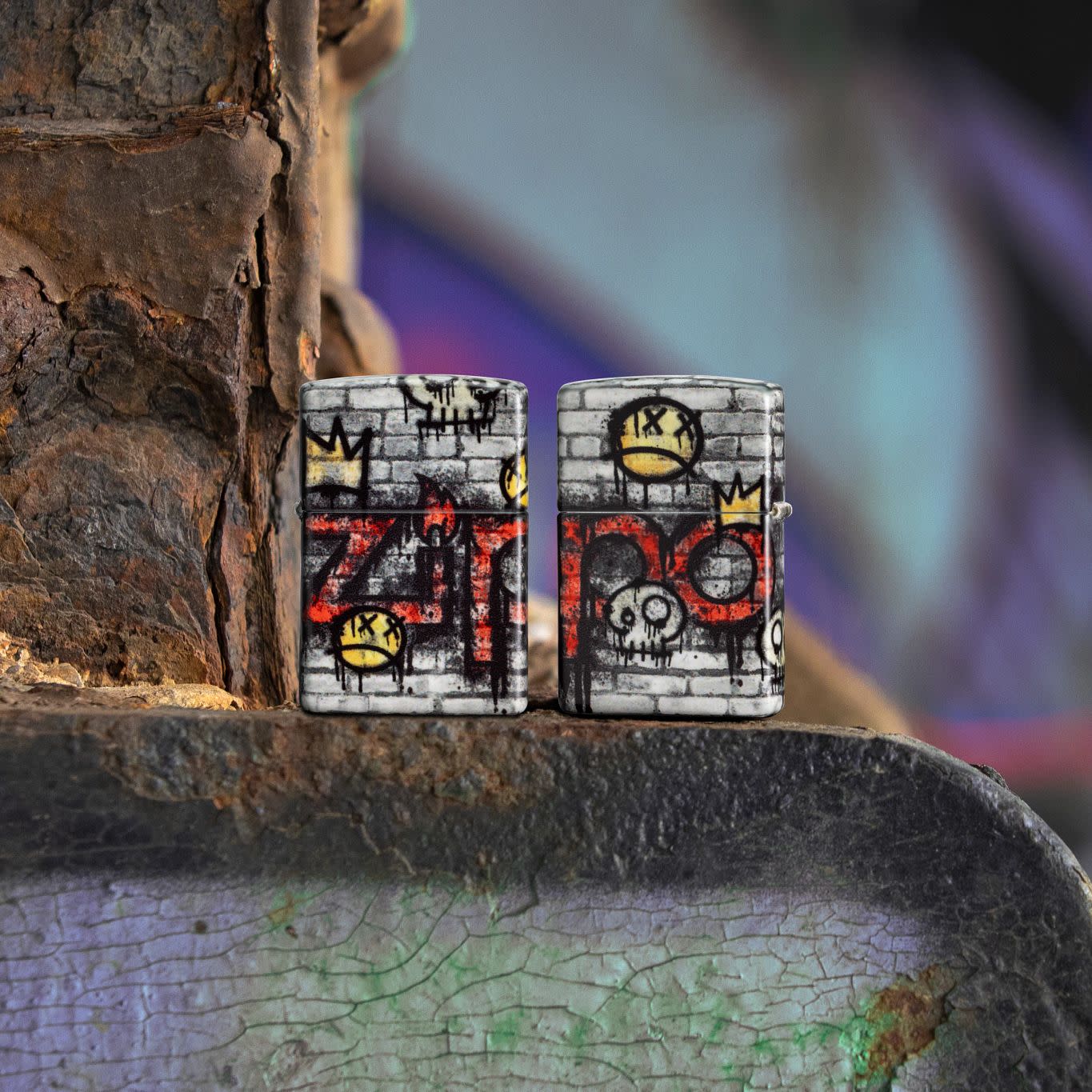 Lifestyle image of two Zippo Graffiti King Design 540 Matte Windproof Lighters, one showing the front of the lighter and the other showing the back, both standing on a rusted sign.