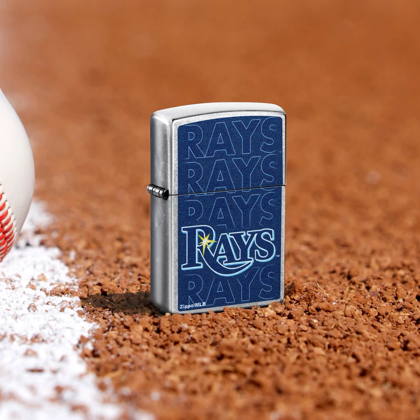 Lifestyle image of Zippo MLB® Tampa Bay Rays Street Chrome Windproof Lighter standing in the dirt on a baseball field.