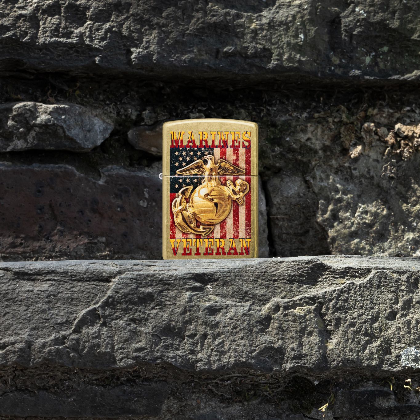Lifestyle image of Zippo U.S. Marine Corps Veteran Design Street Brass Windproof Lighter standing on stone stairs while showing the front of the lighter. 

