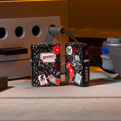 Lifestyle image of two Zippo Notebook Design 540 Matte Windproof Lighters, one showing the front of the lighter and the other showing the back, surrounded by a retro gaming system.