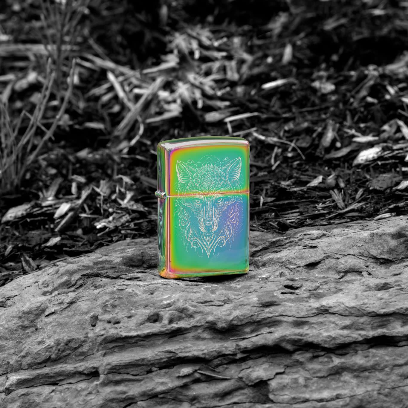 Lifestyle image of Zippo Mystic Wolf Design Multi Color Windproof Lighter standing on a rock in a black and white scene.