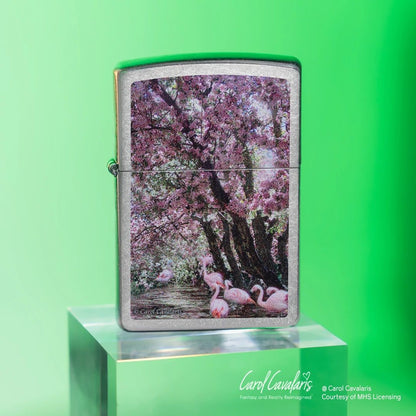 Lifestyle image of Zippo Carol Cavalaris Flamingo Lagoon Design Street Chrome Windproof Lighter standing on a clear cube showing the front of the lighter in front of an ombre green background. 

