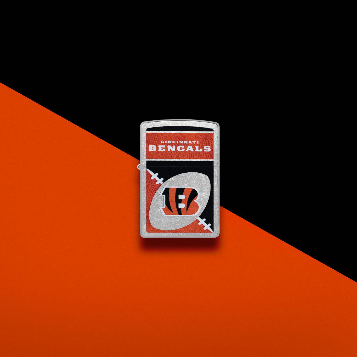 Lifestyle image of Zippo NFL Cincinnati Bengals Street Chrome Windproof Lighter set on an orange and black background.