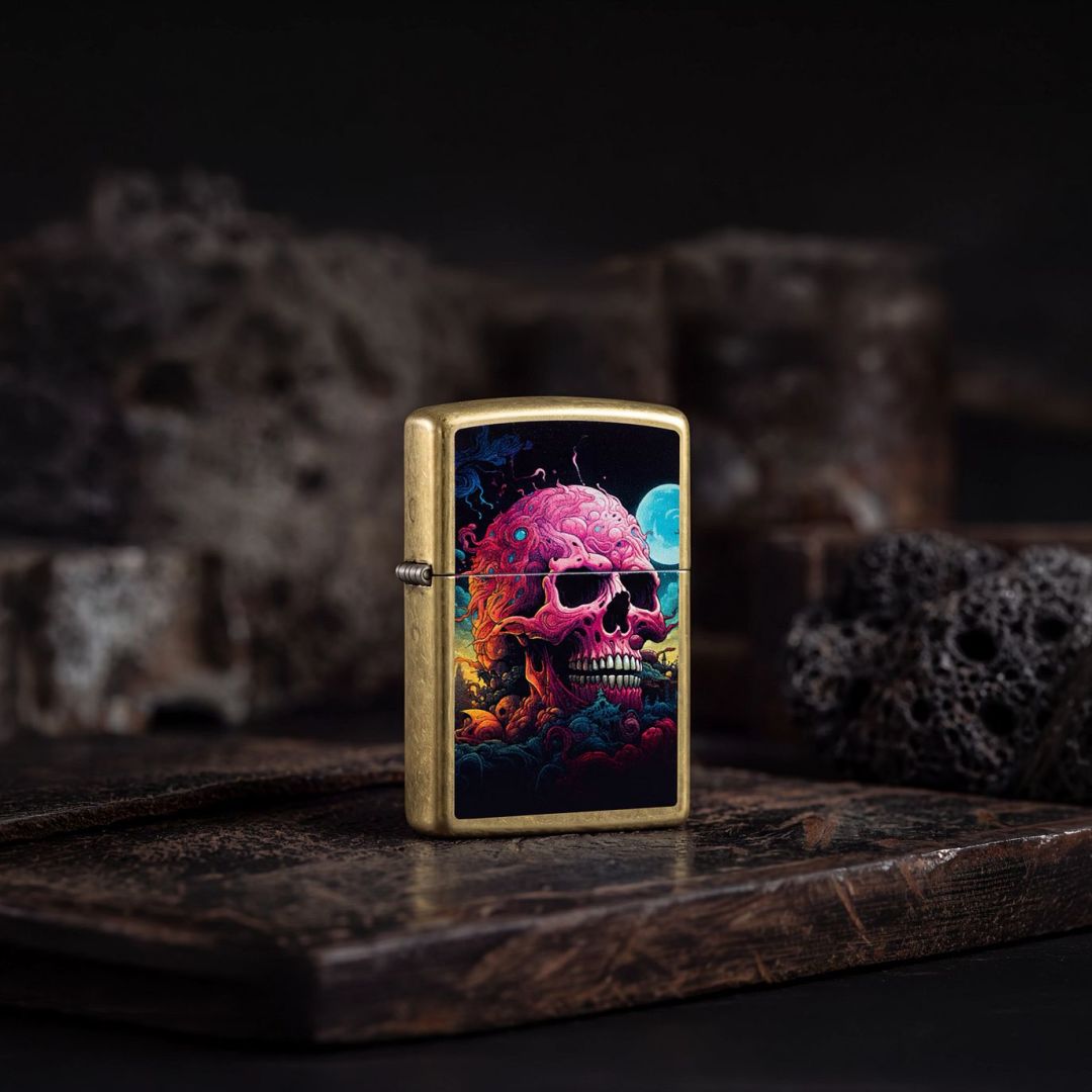 Lifestyle image of Zippo Cosmic Skull Design Street Brass Windproof Lighter standing on a wooden surface showing the front and hinge side of the lighter with an out of focus spooky dark background. 

