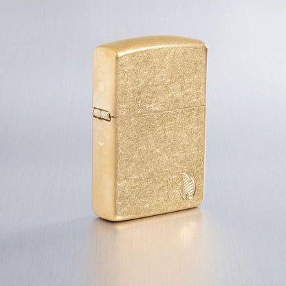 Lifestyle image of Zippo Armor® Series Flame Tumbled Brass Windproof Lighter on a light gray background.