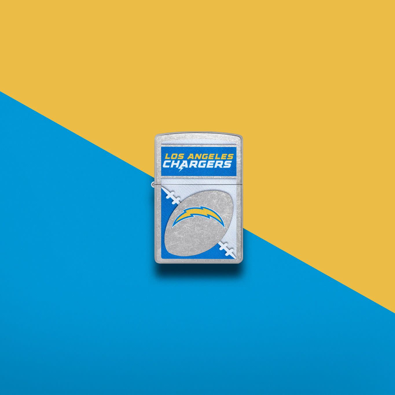 Lifestyle image of Zippo NFL Los Angeles Chargers Street Chrome Windproof Lighter set on a blue and yellow background.