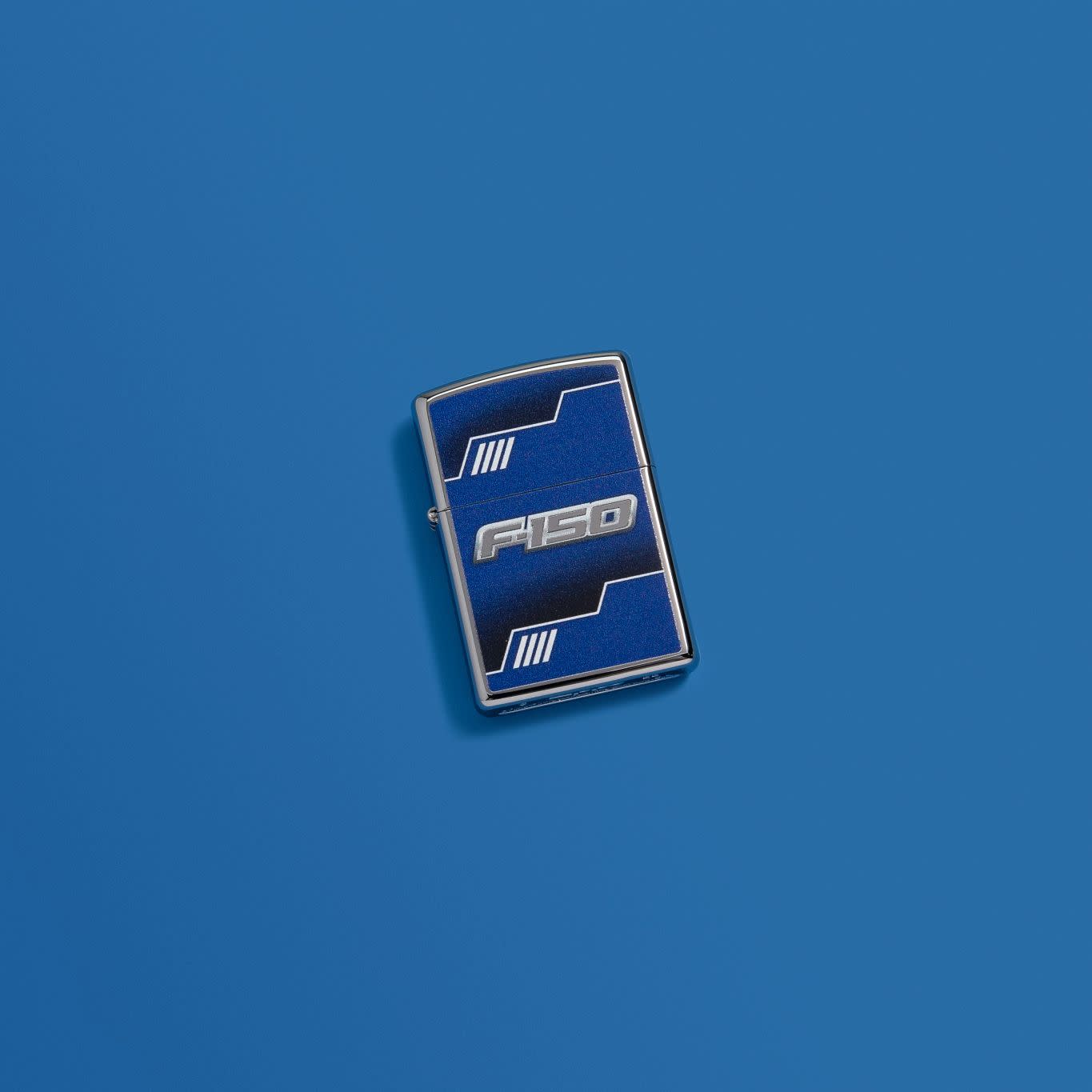 Lifestyle image of Ford F150 Truck High Polish Chrome Windproof Lighter laying on a blue background.