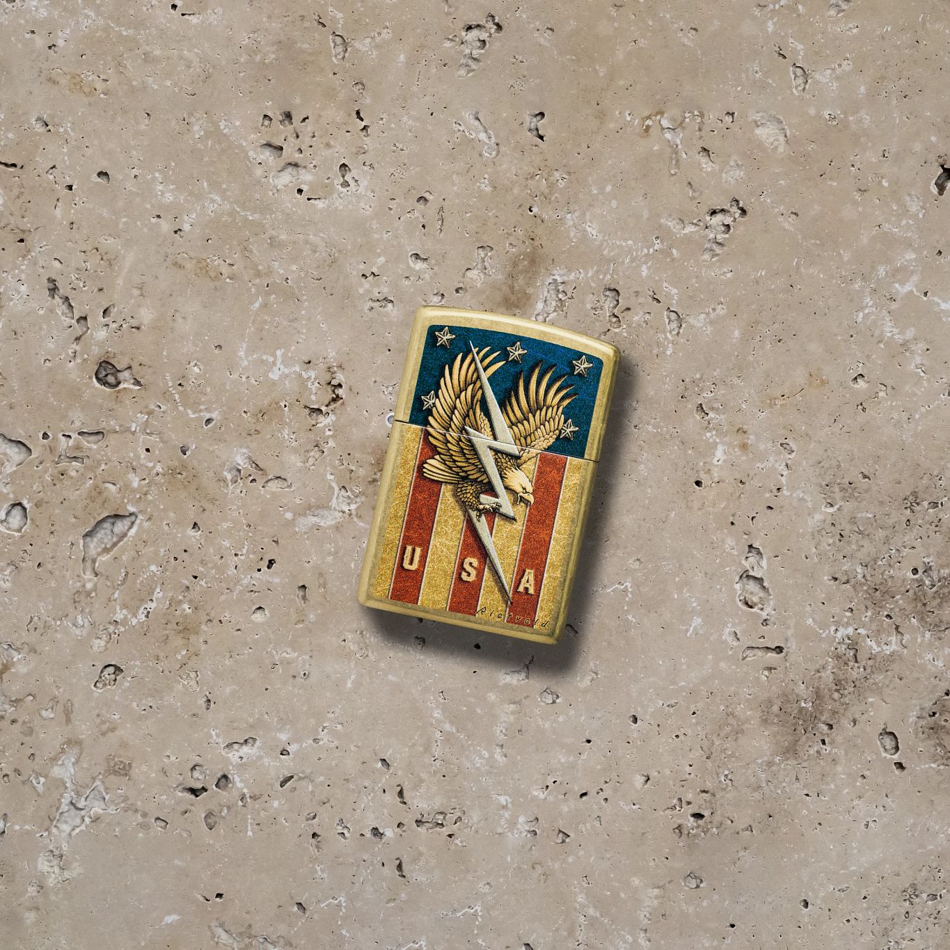 Lifestyle image of Zippo Rietveld USA Design Street Brass Windproof Lighter lying on a stone surface showing the front of the lighter. 

