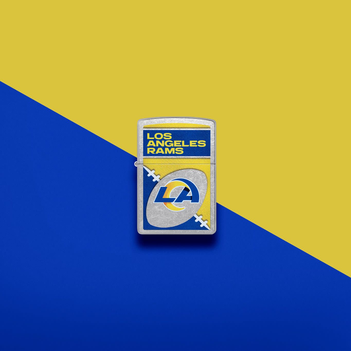 Lifestyle image of Zippo NFL Los Angeles Rams Street Chrome Windproof Lighter set on a blue and yellow background.