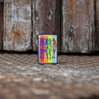 Lifestyle image of Zippo KISS® Fly Flag Design Street Chrome Windproof Lighter standing on a textured metal floor in front of an old, weathered wooden door showing the front of the lighter. 

