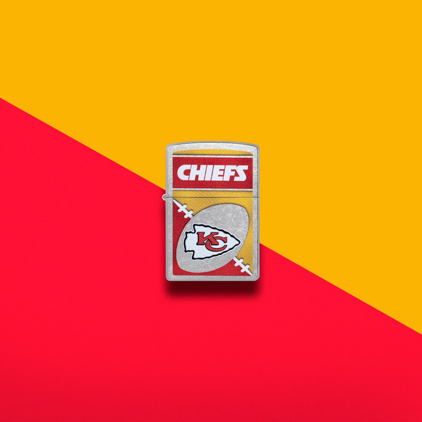 Lifestyle image of Zippo NFL Kansas City Chiefs Street Chrome Windproof Lighter set on a red and gold background.