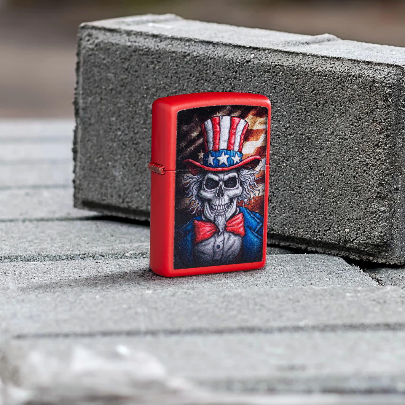 Lifestyle image of Zippo Uncle Skeleton Design Red Matte Windproof Lighter standing on a pallet of cement blocks with one block behind it.