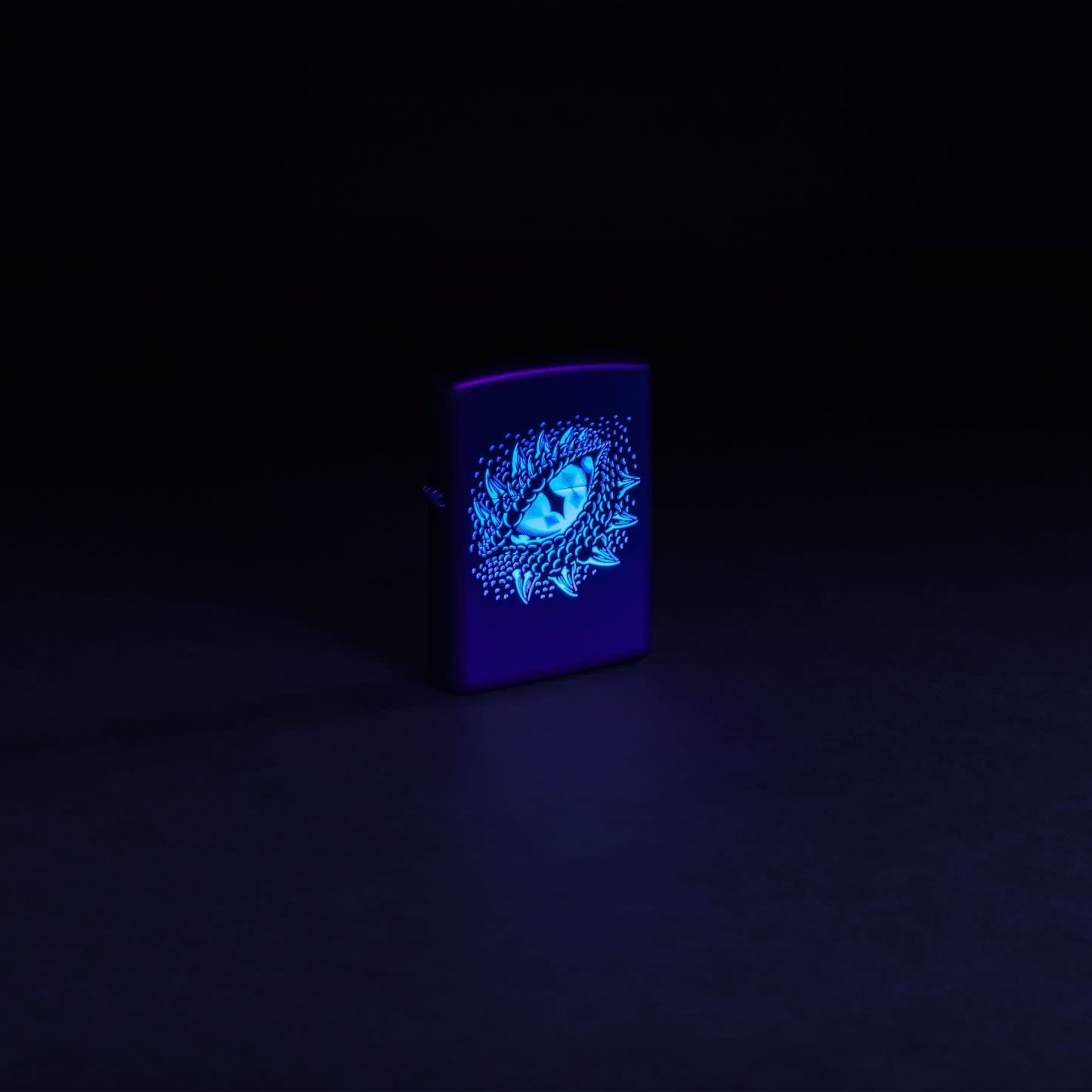 Glamour shot of Zippo Black Light Dragon Eye Design Black Matte Windproof Lighter  glowing with a black light.