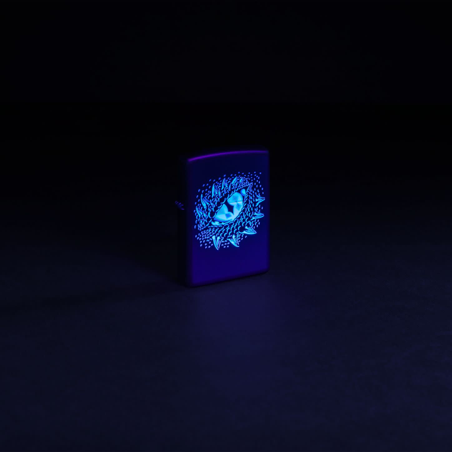 Glamour shot of Zippo Black Light Dragon Eye Design Black Matte Windproof Lighter  glowing with a black light.