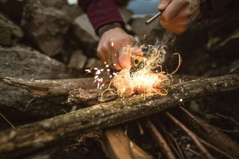 Mag strike lighting tinder shreds over logs