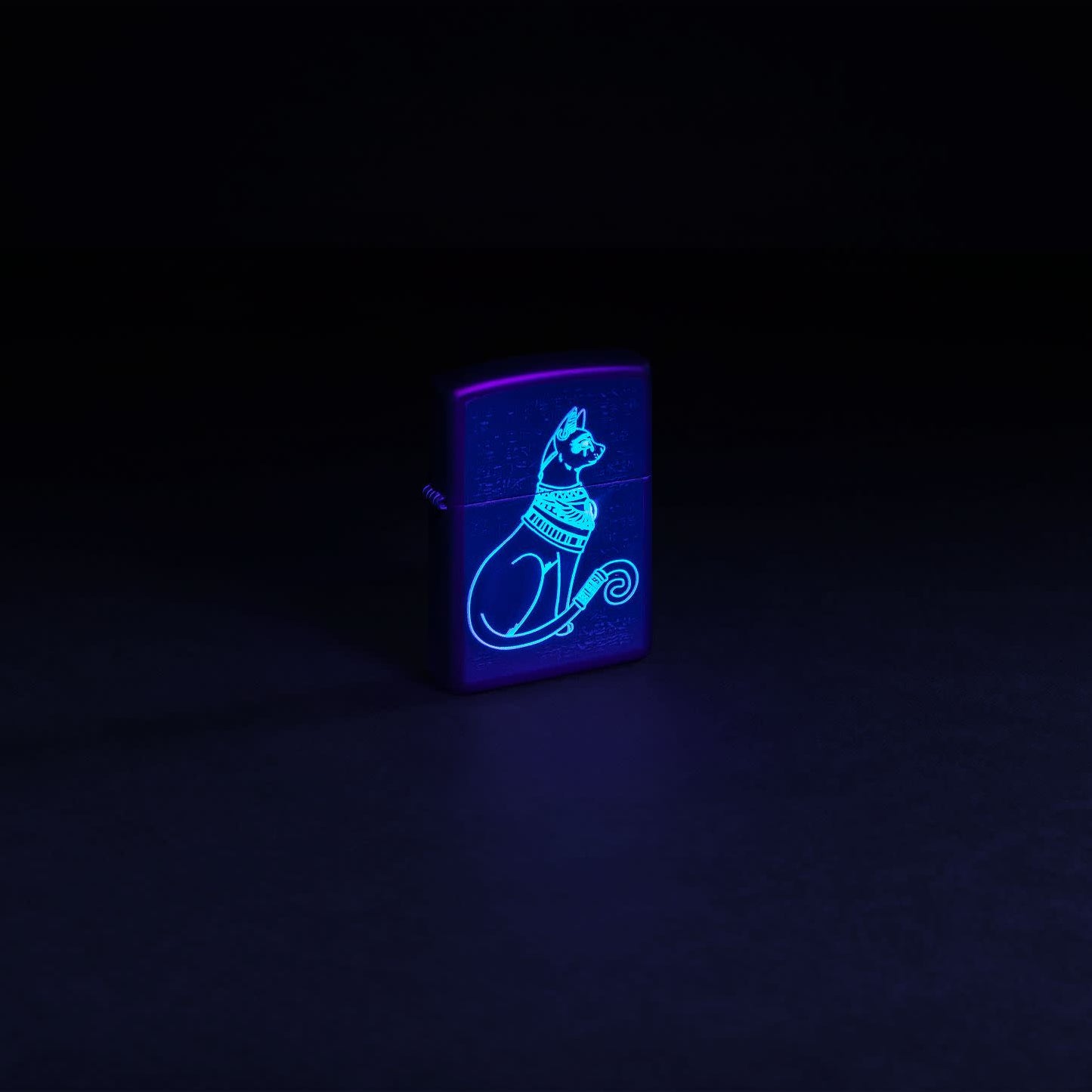 Glamour shot of Zippo Black Light Spiritual Cat Design Black Matte Windproof Lighter glowing with a black light.