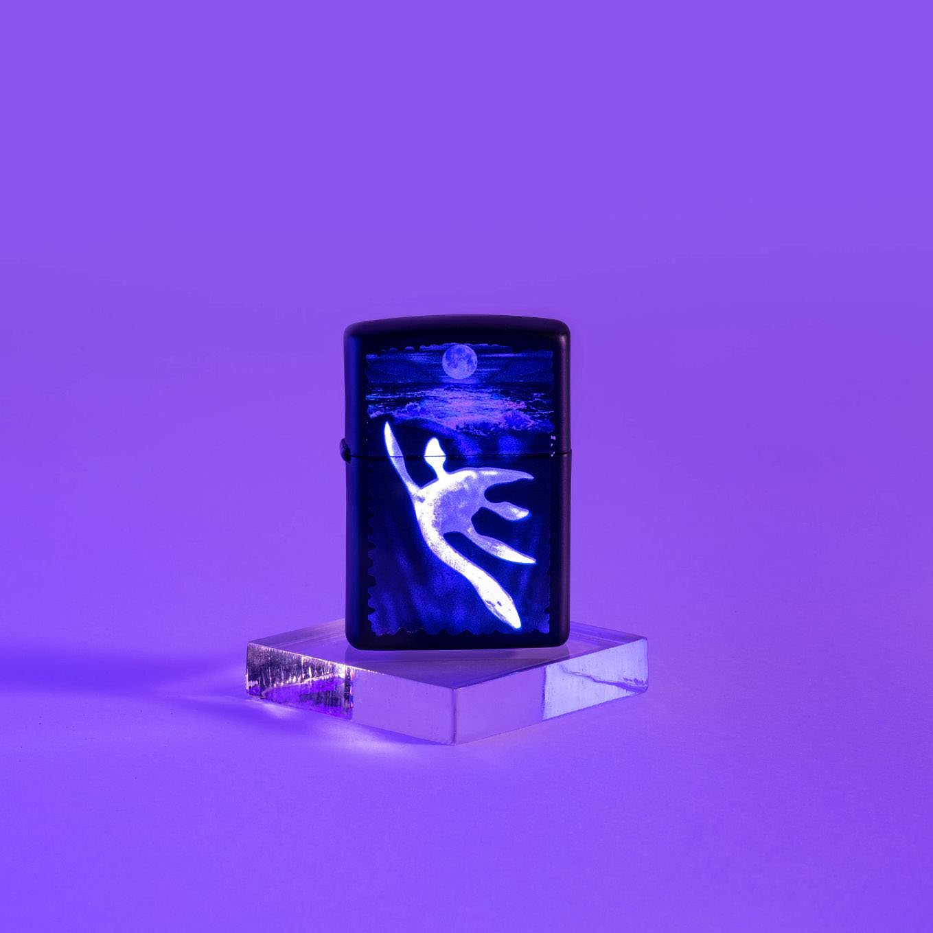 Lifestyle image of Black Light Loch Ness Design Black Matte Windproof Lighter glowing under a black light.