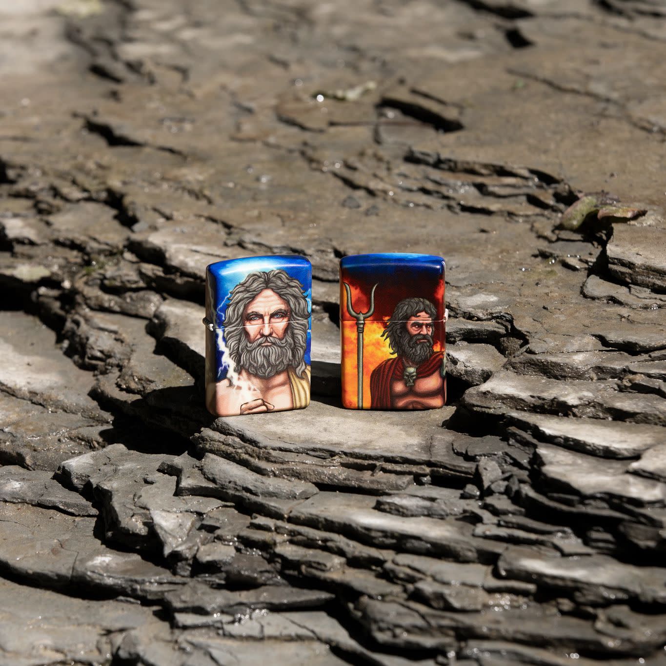 Lifestyle image of two Greek God Clash Design Glow in the Dark 540 Color Windproof Lighters standing on a rock.