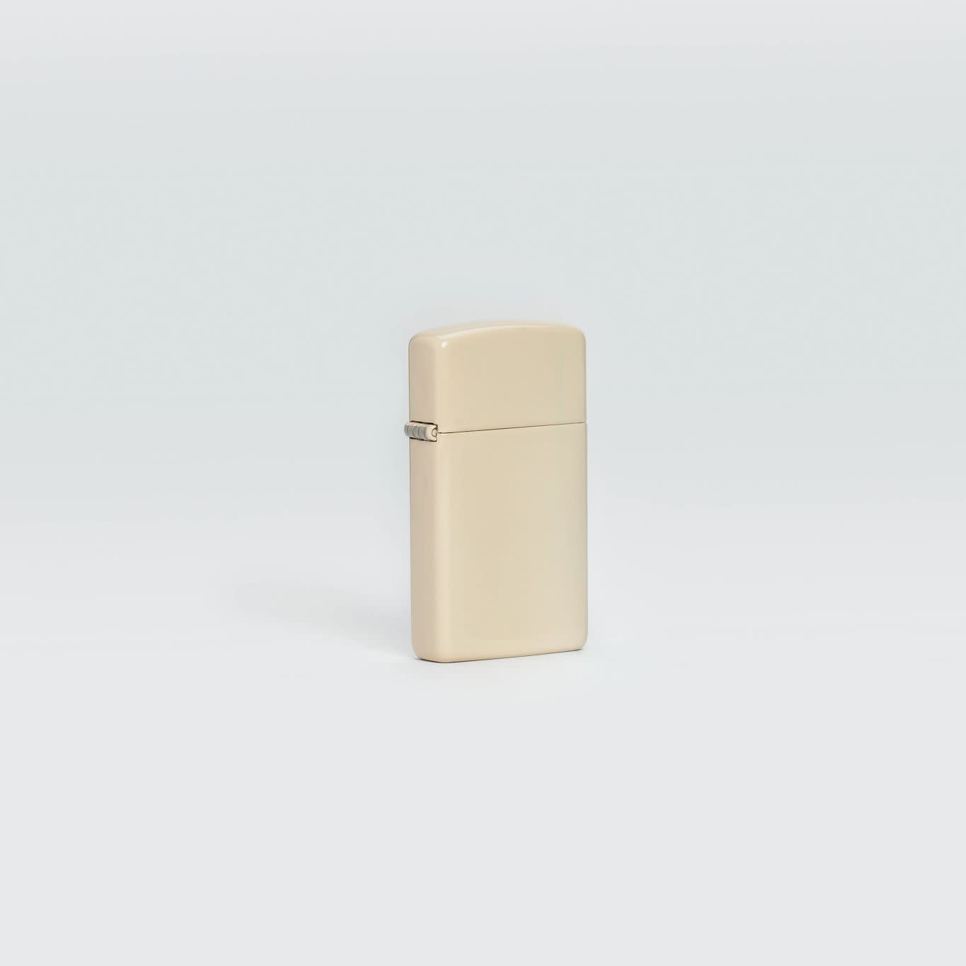 Lifestyle image of Slim® Flat Sand Zippo Logo Windproof Lighter standing in a grey scene.