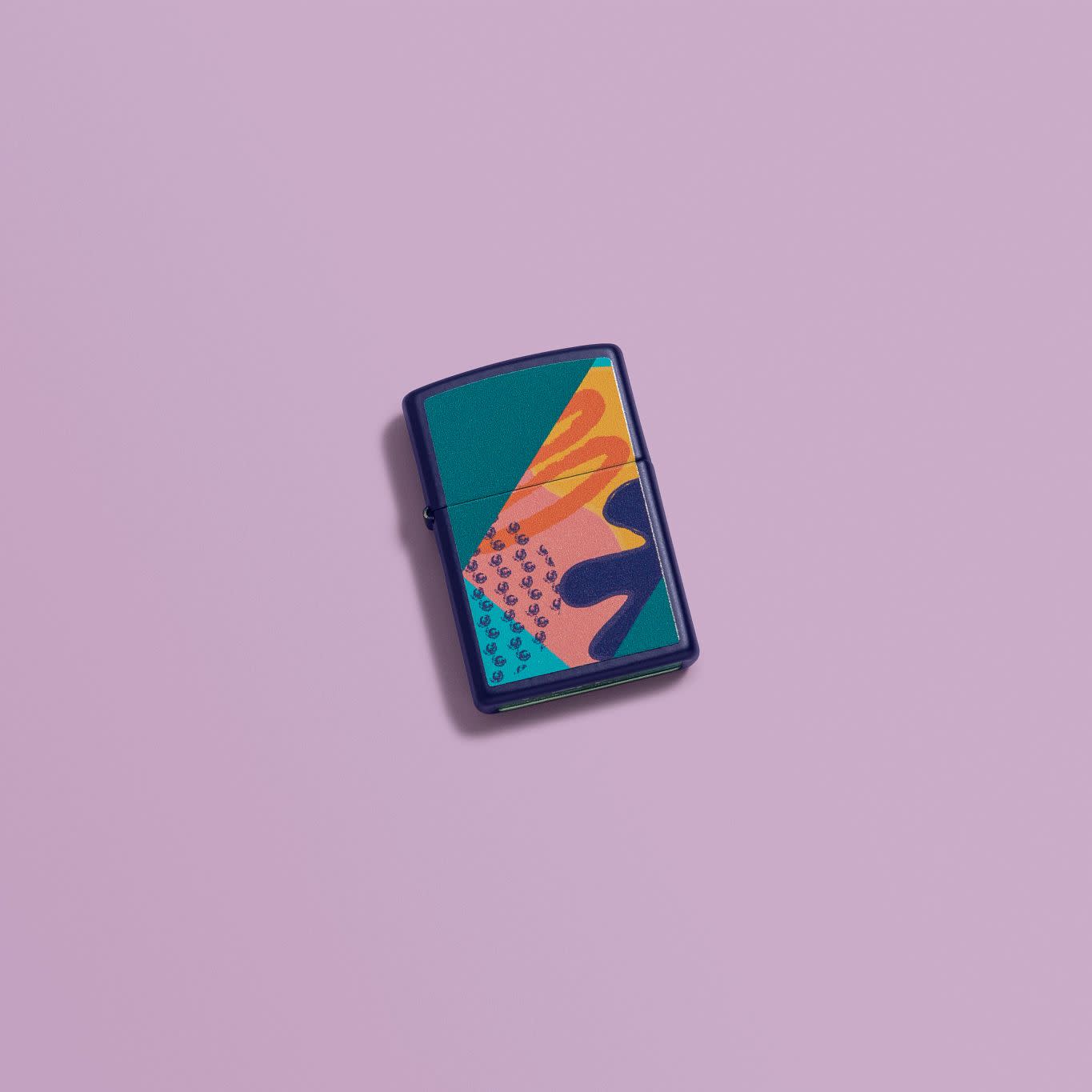 Lifestyle image of Retro Pattern Design Navy Matte Windproof Lighter laying on a purple background.