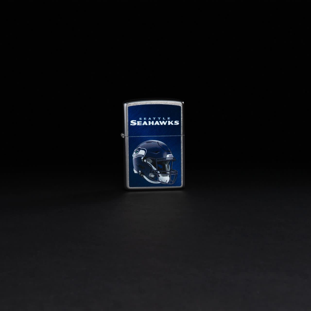 Lifestyle image of NFL Seattle Seahawks Helmet Street Chrome Windproof Lighter standing in a black background.