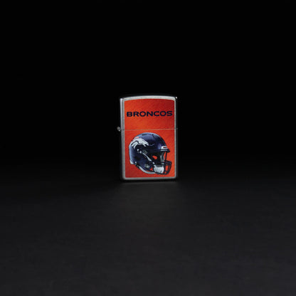 Lifestyle image of NFL Denver Broncos Helmet Street Chrome Windproof Lighter standing in a black background.