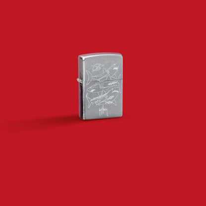 Glamour shot of Zippo Guy Harvey Shark Design Street Chomre Windproof Lighter standing in a red scene.