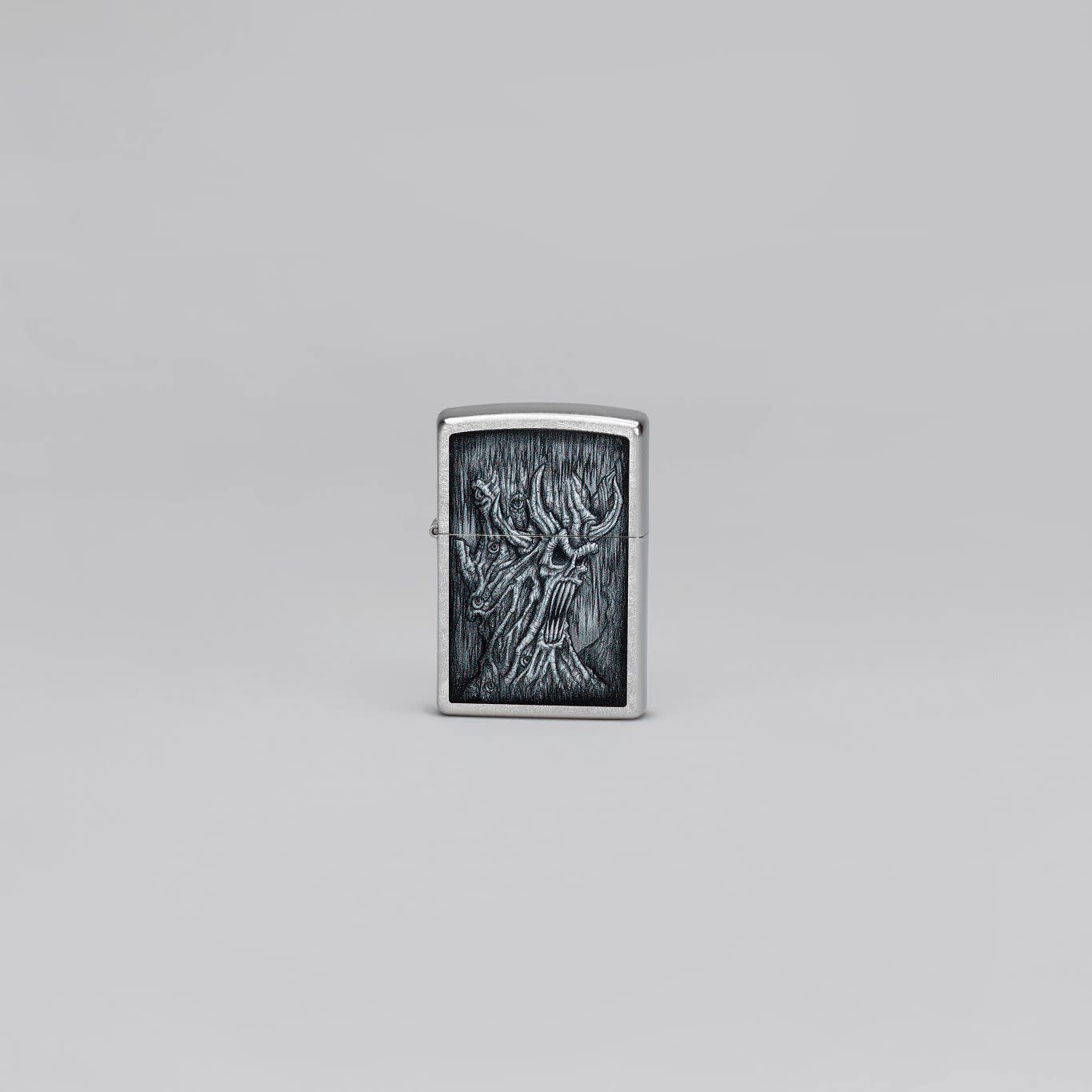 Lifestyle image of Zippo Evil Tree Design Street Chrome Windproof Lighter standing in a grey scene.