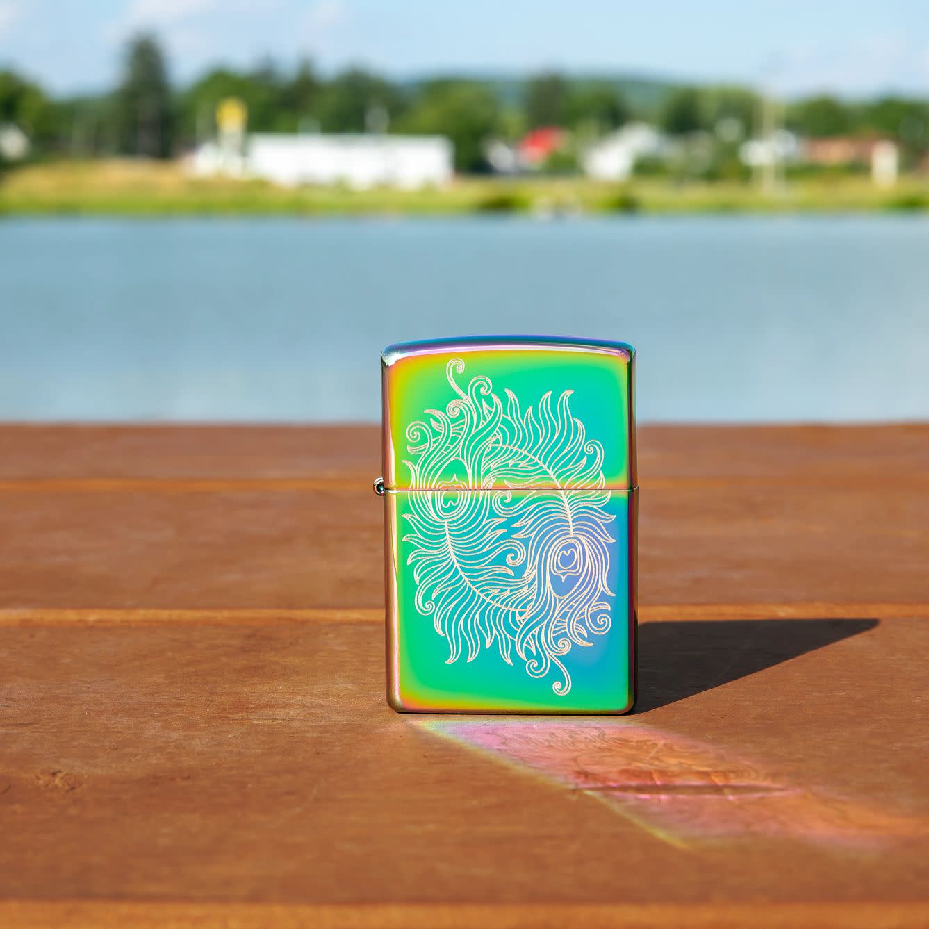 Lifestyle image of Laser Engraved Spiritual Design Multi Color Windproof Lighter standing on a railing with a lake behdind it.