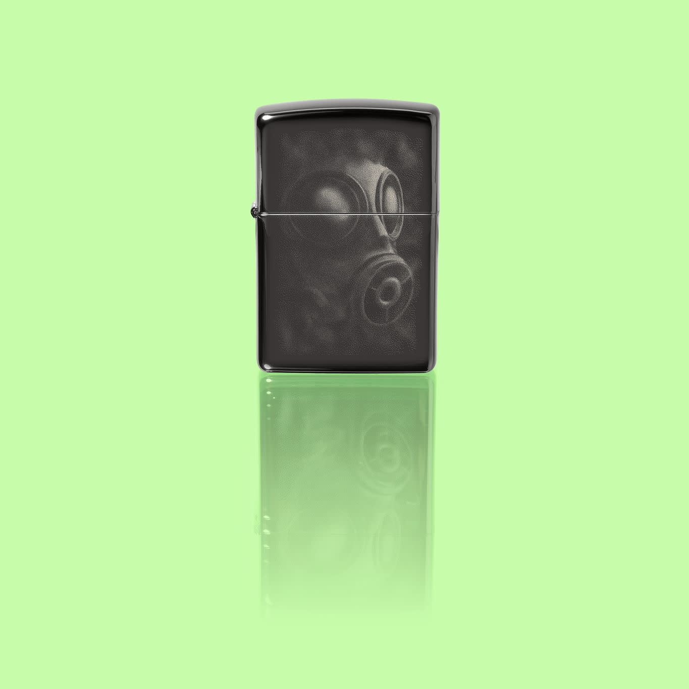 Glamour shot of Zippo Gas Mask Design High Polish Black Pocket Lighter standing in a green scene.