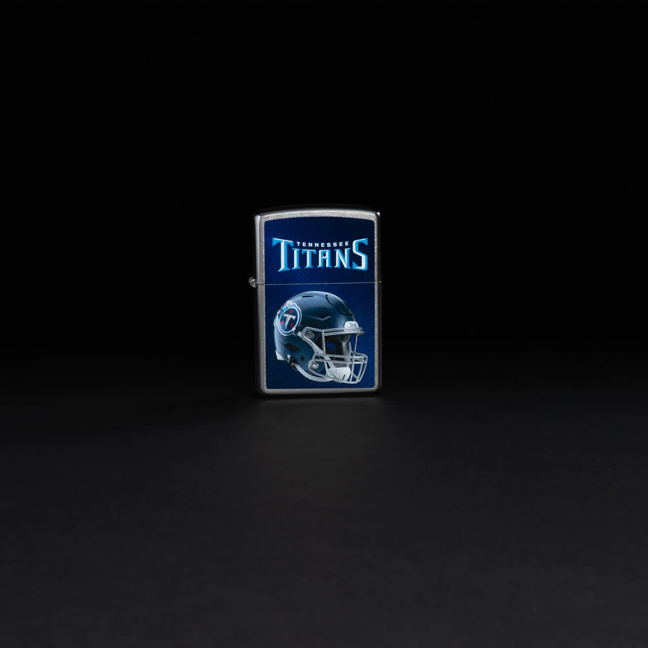 Lifestyle image of NFL Tennessee Titans Helmet Street Chrome Windproof Lighter standing in a black background.