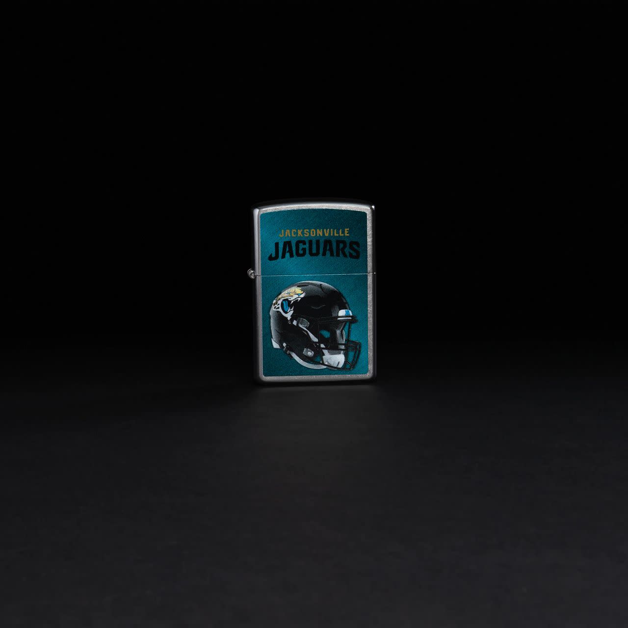 Lifestyle image of NFL Jacksonville Jaguars Helmet Street Chrome Windproof Lighter standing in a black background.